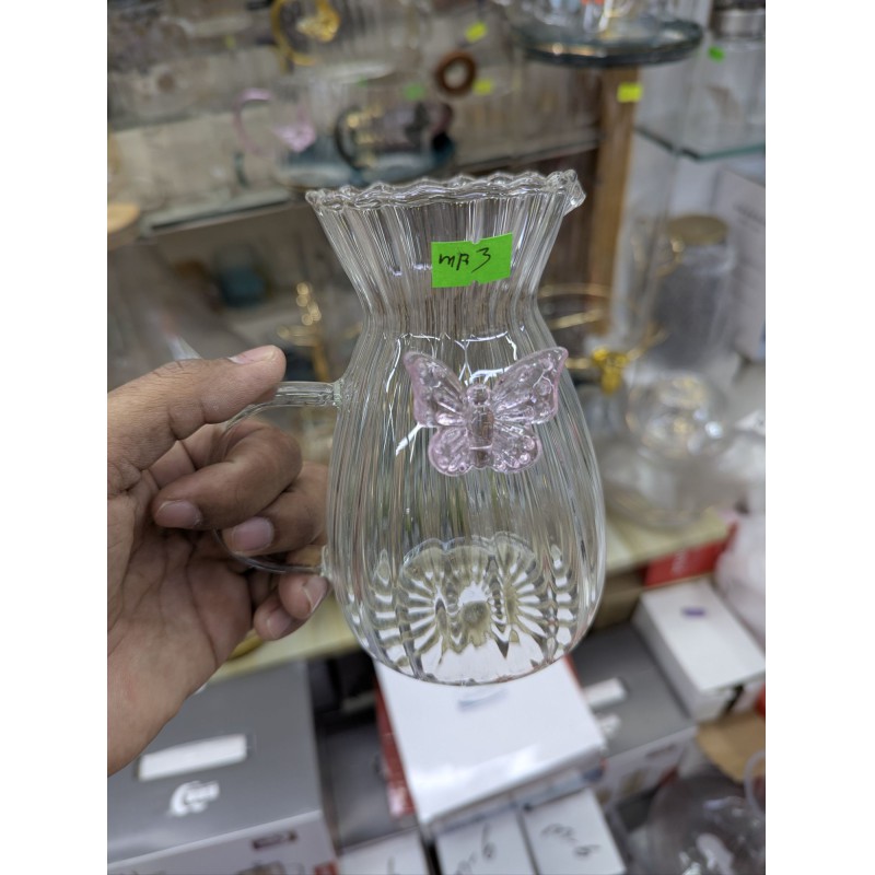 Picture of Elegant fluted borosilicate glass pitcher with pink butterfly motif and scalloped rim for serving fresh orange juice lemonade or iced tea at sophisticated garden parties brunch gatherings and stylish home dining events.
